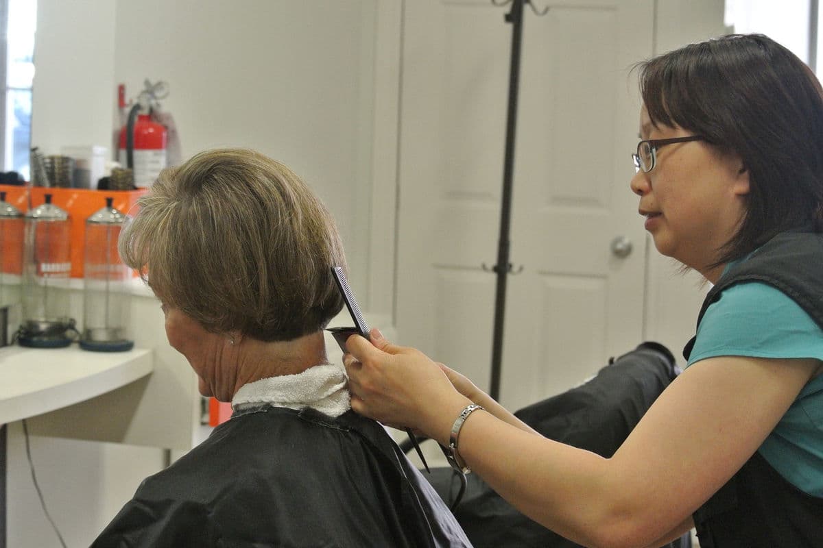 Hair stylist trimming hair in salon