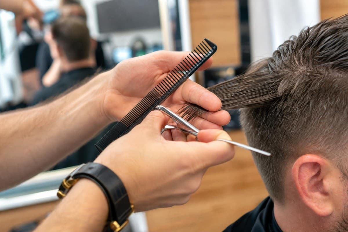 Close-up of a Topcuts stylist trimming hair with scissors and a comb.